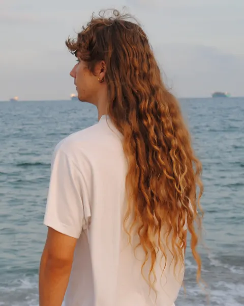 De perfil frente al mar, con el pelo largo al viento